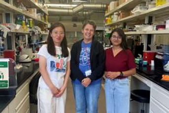 Three people facing a camera in a lab