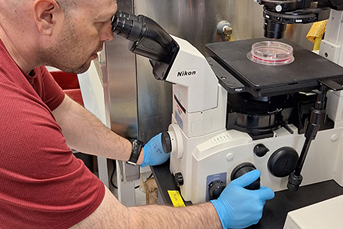 A man peering into a piece of lab equipment
